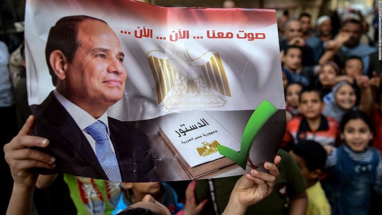 投票所の外で投票を呼び掛けるポスターを持つ男性/MOHAMED EL-SHAHED/AFP/AFP/Getty Images