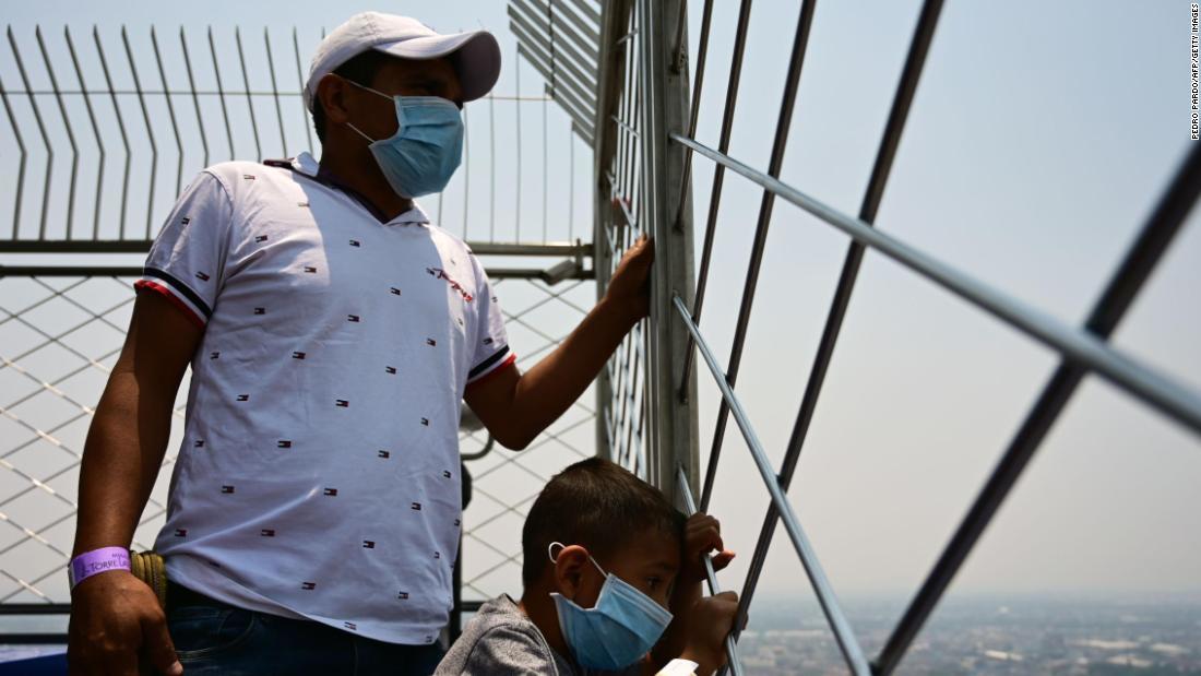 大気汚染が悪化する中、メキシコ市の高層タワー、ラテンアメリカタワーの展望場所から町を眺める人々＝１４日/Pedro Pardo/AFP/Getty Images