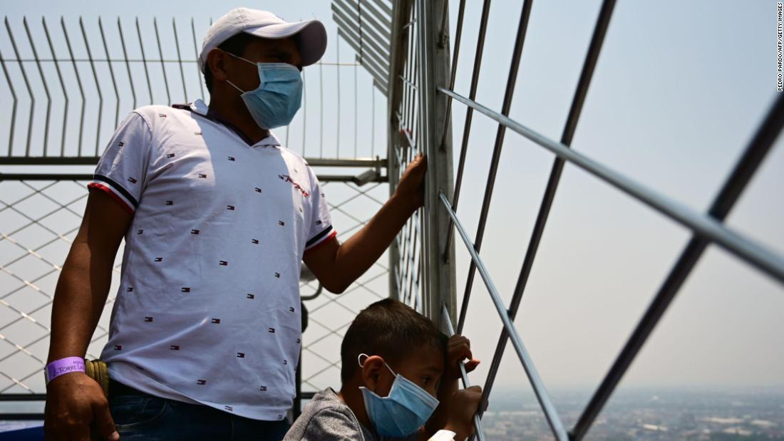 大気汚染が悪化する中、メキシコ市の高層タワー、ラテンアメリカタワーの展望場所から町を眺める人々=14日/Pedro Pardo/AFP/Getty Images