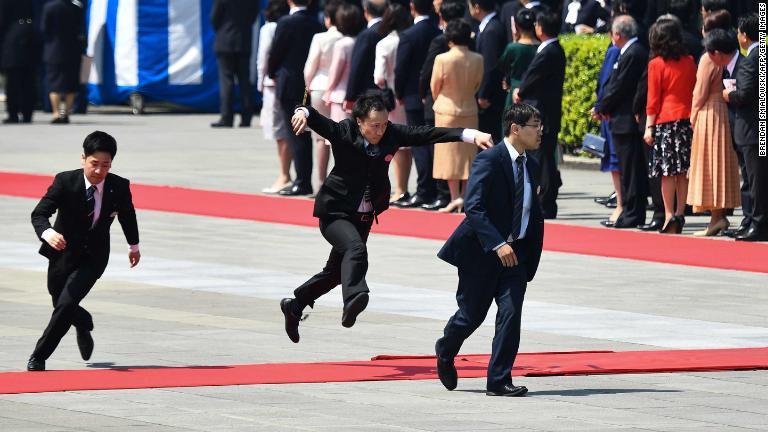 歓迎式典に向けて赤いじゅうたんを調整した後それを飛び越えるスタッフ/Brendan Smialowski/AFP/Getty Images