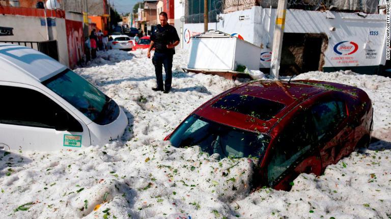 警官が氷に埋まった車両の脇に立っている/Ulises Ruiz/AFP/Getty Images