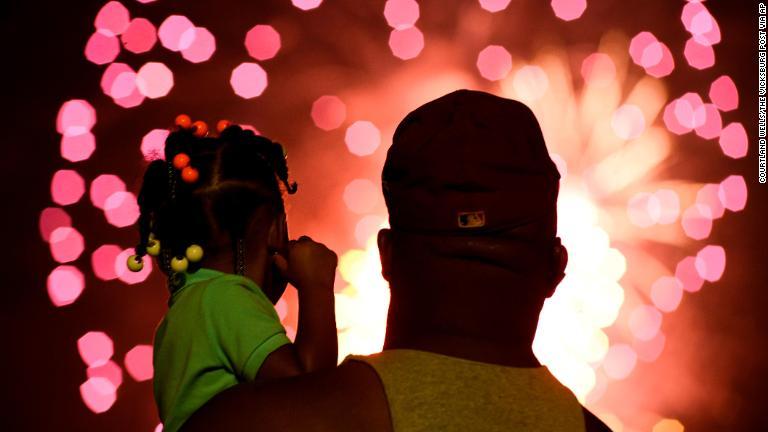 ミシシッピ州ビクスバーグで名付け娘と花火を眺める男性/Courtland Wells/The Vicksburg Post via AP