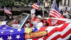 愛国心あふれる外装の車でパレードに参加する男性