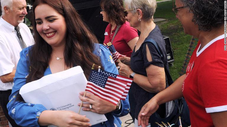 米国の市民権を取得した女性を祝福して星条旗を手渡す＝フロリダ州ウィンターパーク/Paul Hennessy/NurPhoto via Getty Images
