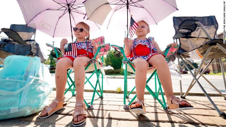 パラソルの下でパレードを待つ幼い姉妹＝マサチューセッツ州ピッツフィールド/Ben Garver/The Berkshire Eagle/AP
