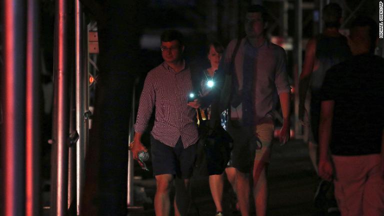 携帯電話のライトを使って移動する人たち/Michael Owens/AP