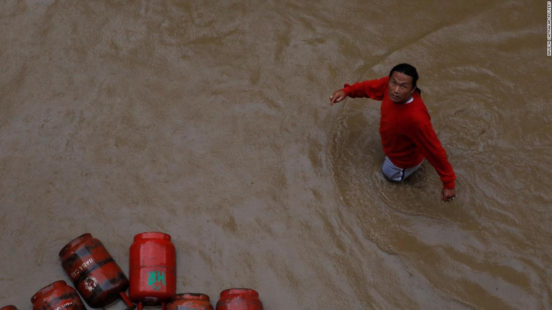 冠水した集落でガスボンベの脇を通り過ぎる男性=12日、ネパール・カトマンズ/Navesh Chitrakar/Reuters