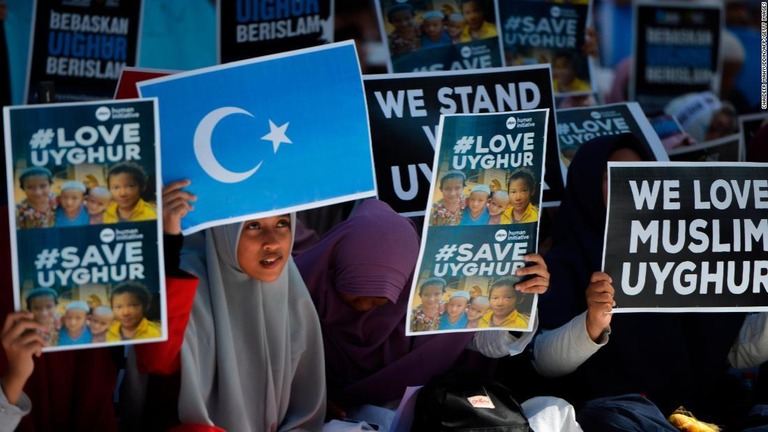 ウイグルの旗を掲げ、中国政府による弾圧に抗議する女性/CHAIDEER MAHYUDDIN/AFP/Getty Images