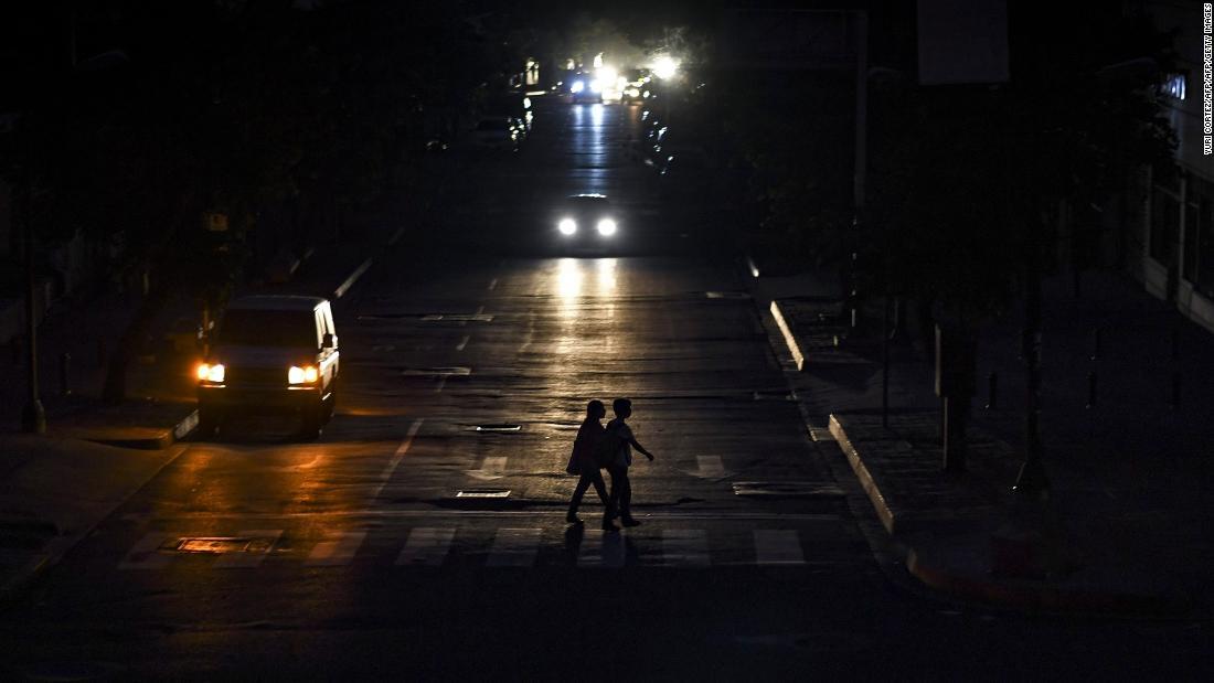 首都カラカスの道路を横断する人々＝２２日/YURI CORTEZ/AFP/AFP/Getty Images