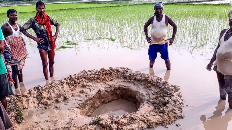 隕石と見られる物体の周囲にできたクレーターのまわりに集まる住民＝インド・ビハール州マハデバ村/STR/AFP/Getty Images