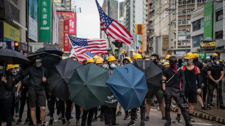 香港で、米国国旗を掲げて抗議デモに参加する人々/Getty Images/Getty Images AsiaPac/Getty Images