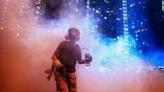 マスクをかぶって催涙ガスに抵抗するデモ参加者＝４日