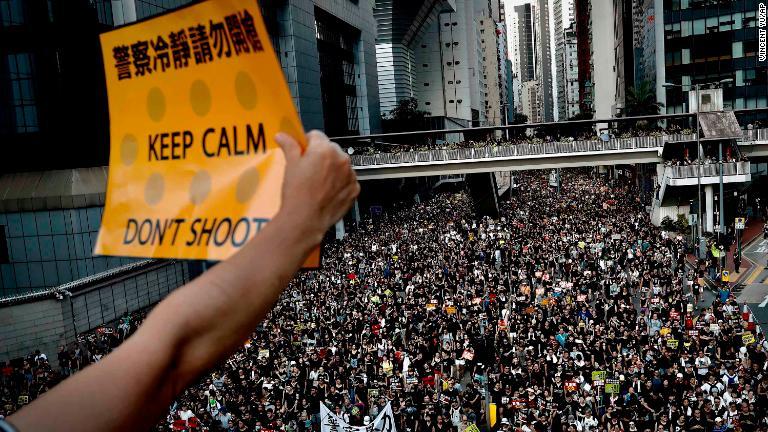 プラカードを掲げるデモ参加者＝７月１日/Vincent Yu/AP