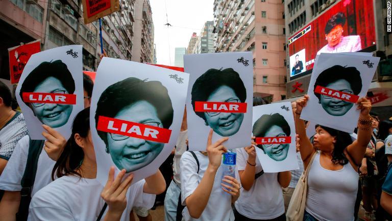 林鄭月娥（キャリー・ラム）行政長官を批判したポスターを掲げる人たち＝６月９日/Kin Cheung/AP