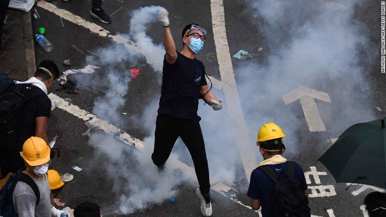 催涙ガスの缶を投げ返すデモ参加者＝６月１２日/Anthony Wallace/AFP/Getty Images