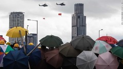 中国と香港の旗を掲げて飛ぶヘリコプター＝７月１日