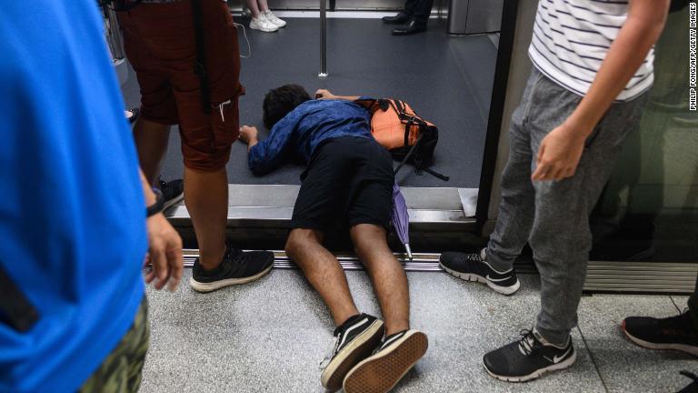 デモの一環で列車のドア部分に倒れ込む男性＝５日/Philip Fong/AFP/Getty Images