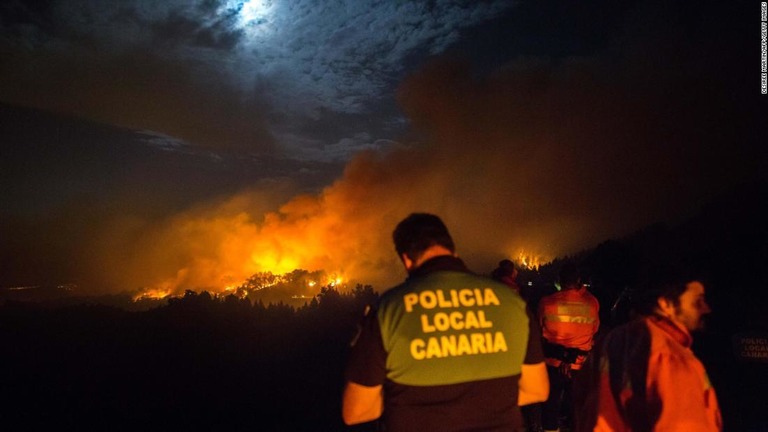 火災の様子を確認する警官ら＝１７日/Desiree Martin/AFP/Getty Images