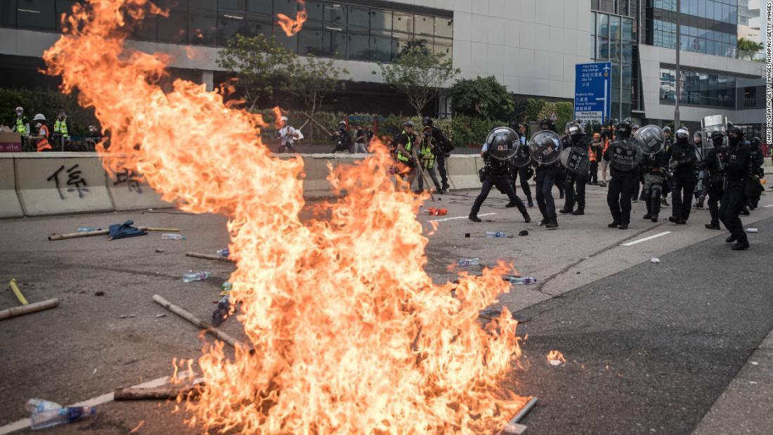 燃え盛る炎を前に後退する警官隊＝２４日、香港・観塘/Chris McGrath/Getty Images AsiaPac/Getty Images
