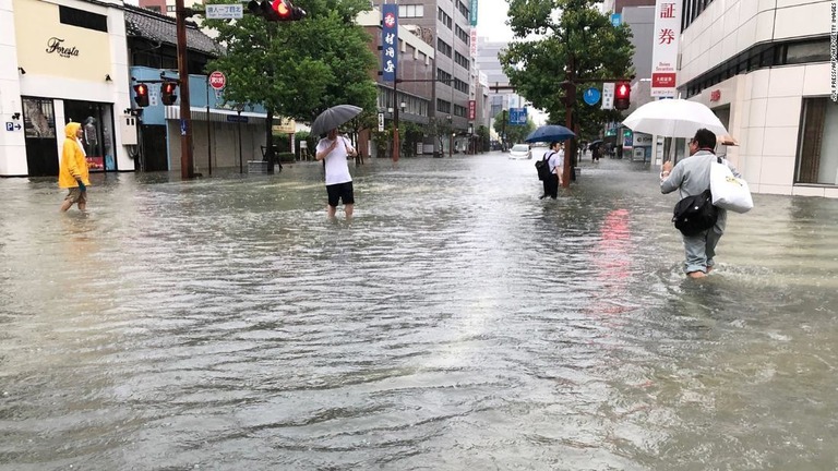 冠水した道路を歩く人たち＝２８日、佐賀県/JIJI PRESS/AFP/AFP/Getty Images