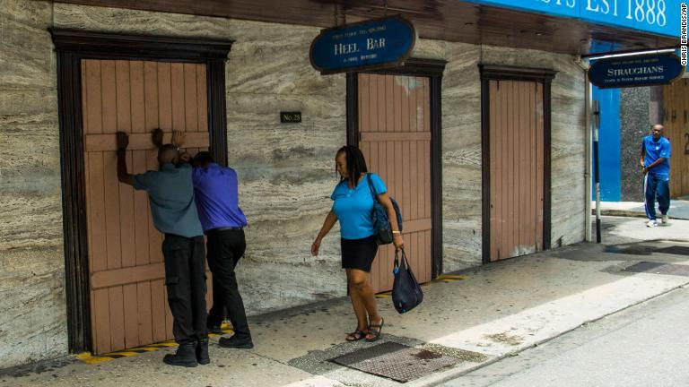 カリブ海の国、バルバドスの首都ブリッジタウンで薬局の入り口を板で防ぐ人々＝２６日/Chris Brandis/AP