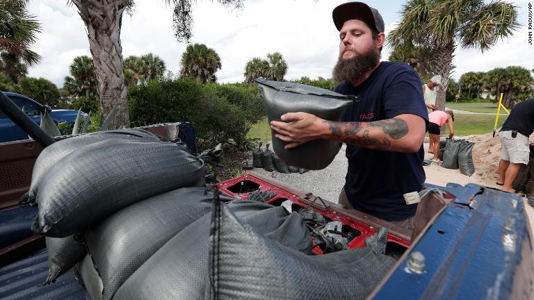 ハリケーン襲来に備え車で土のうを運ぶ男性＝３０日、フロリダ州フラグラービーチ/John Raoux/AP