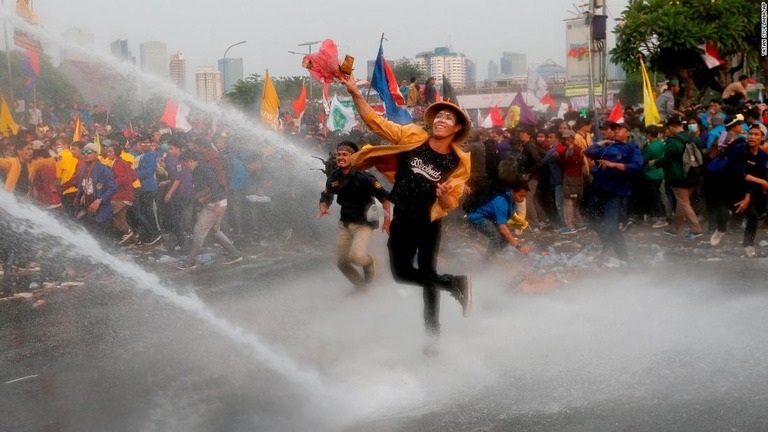 議会前で物を投げる抗議デモ隊。警官隊は放水銃を使用＝２４日、ジャカルタ/Tatan Syuflana/AP