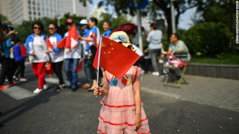 軍事パレードの最中に中国国旗を持つ少女/Hector Retamal/AFP/Getty Images