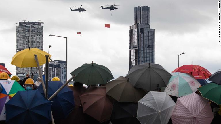 中国と香港の旗を掲げて飛ぶヘリコプター＝７月１日/Kyle Lam/Bloomberg via Getty Images