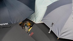 傘のすき間から様子を眺めるデモ参加者＝７月２７日