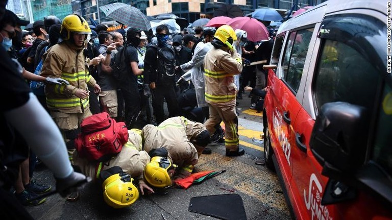 デモ集団へ突っ込んだタクシーの下を調べる救急隊員/Anthony Wallace/AFP/Getty Images