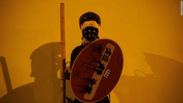 マスクをして盾を構えるデモ参加者/Felipe Dana/AP