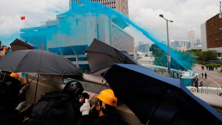 青い染料の入った水を噴射する警察/Kin Cheung/AP