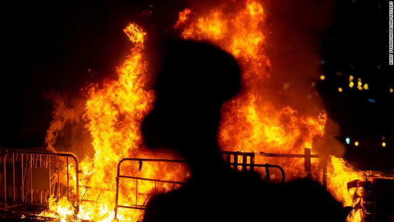 炎の横に立つ反体制派のデモ参加者＝１０月４日/Athit Perawongmetha/Reuters