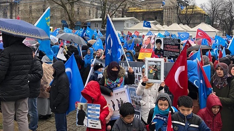中国政府による取り締まりで肉親が行方不明になったと写真を掲げデモ行進する人々＝トルコ・イスタンブール/Isil Sariyuce/CNN