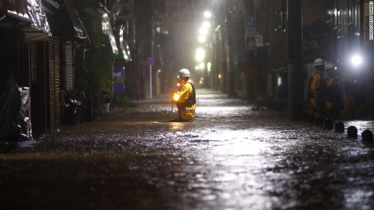 冠水した道路を歩く救急隊員＝１２日、東京都/Kyodo/Getty Images