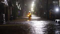 冠水した道路を歩く救急隊員＝１２日、東京都