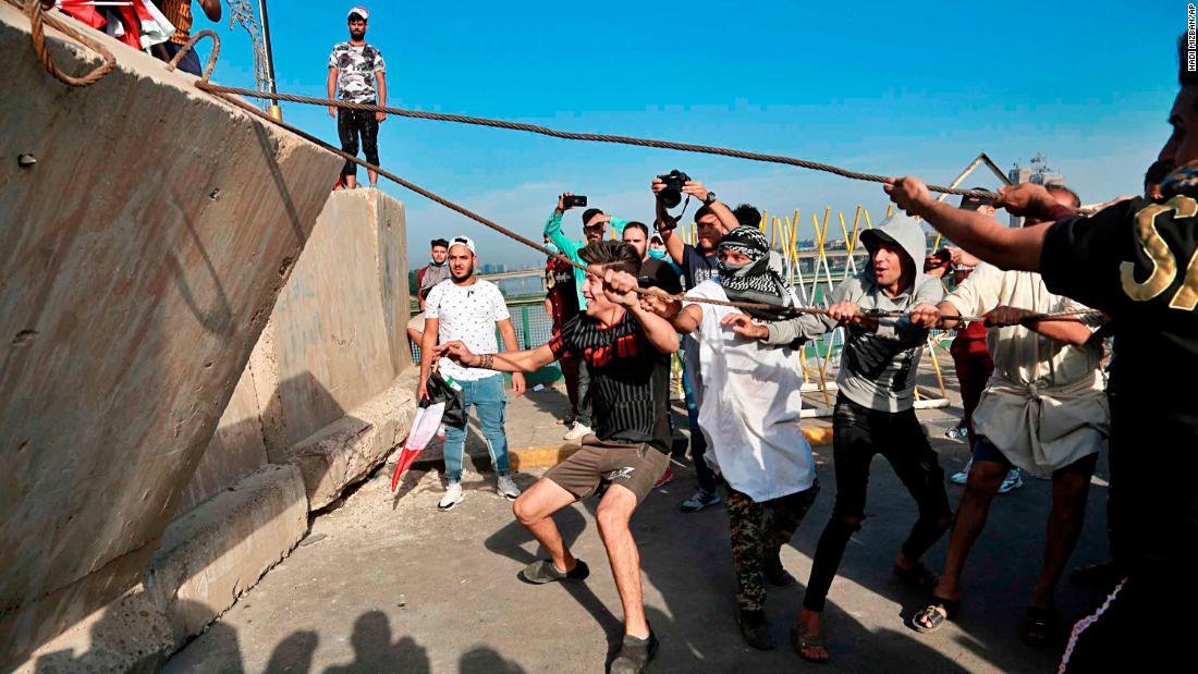 コンクリートの壁を倒し「グリーンゾーン」への進入を試みるデモ参加者たち/Hadi Mizban/AP