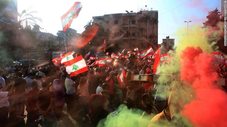 国旗を掲げるデモ参加者＝１９日、サイダ市内/Mahmoud Zayyat/AFP via Getty Images