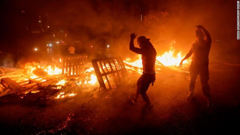 木材などを燃やすデモ参加者たち＝１７日/Anwar Amro/AFP/Getty Images