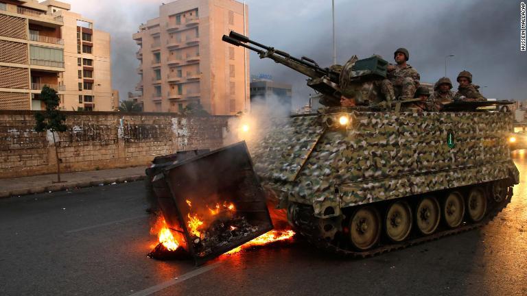 反政府グループによって火をつけられたごみ入れを移動させる装甲兵員輸送車＝２８日/Hussein Malla/AP