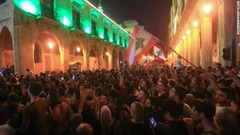 政府官邸の外で国旗を掲げるデモ参加者たち＝１７日、ベイルート