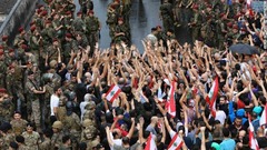 国旗を掲げてスローガンを叫ぶ反政府グループと対峙するレバノン軍＝２３日