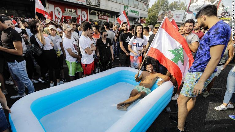 主要道路上に設置したプール内で国旗を掲げる抗議者＝１９日/Joseph Eid/AFP via Getty Images