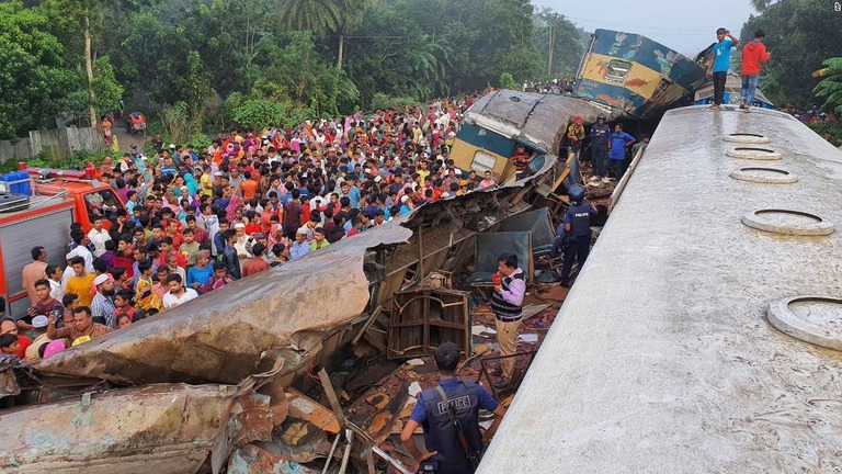 破損した車両の近くに集まった人々＝１２日、バングラデシュ・ブラーマンバリア/AP