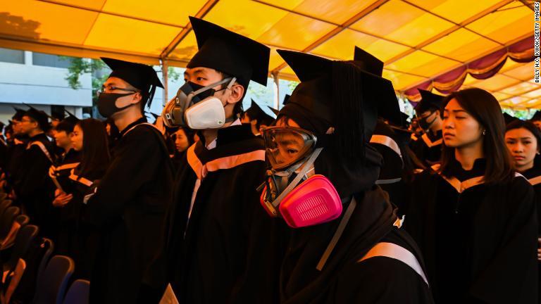 卒業式でガスマスクをする学生ら＝７日、香港/Billy H.C. Kwok/Getty Images