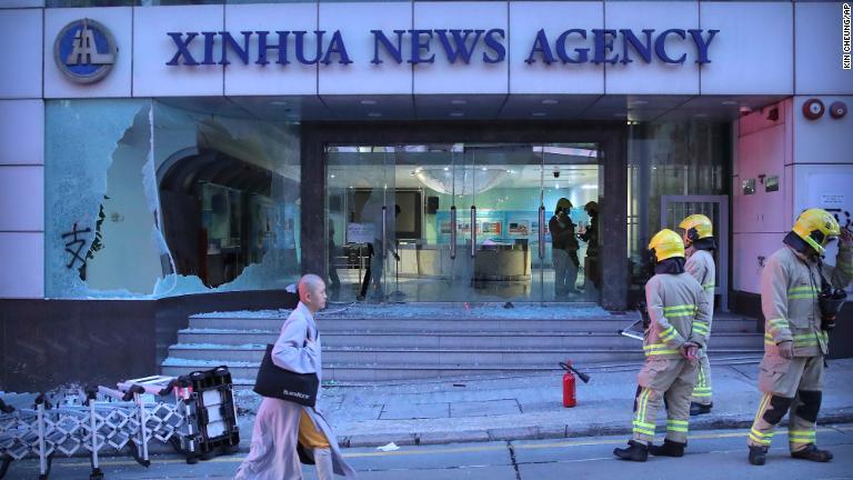 ショーウィンドウが壊された建物前に立つ消防隊員ら/Kin Cheung/AP