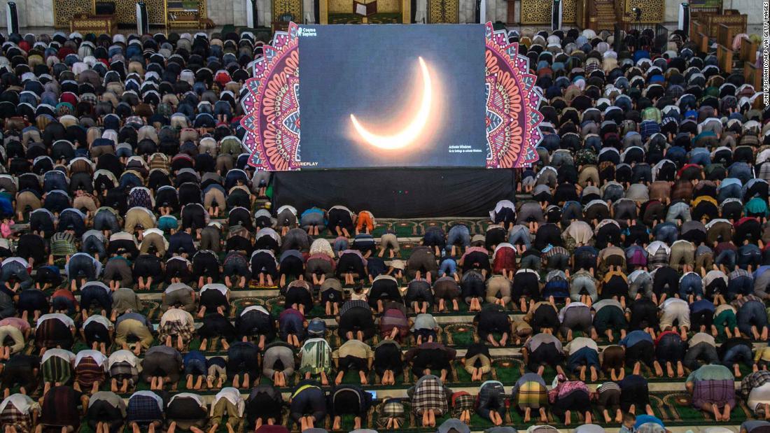 スクリーンの金環日食に祈る人々=インドネシア/Juni Kriswanto/AFP via Getty Images