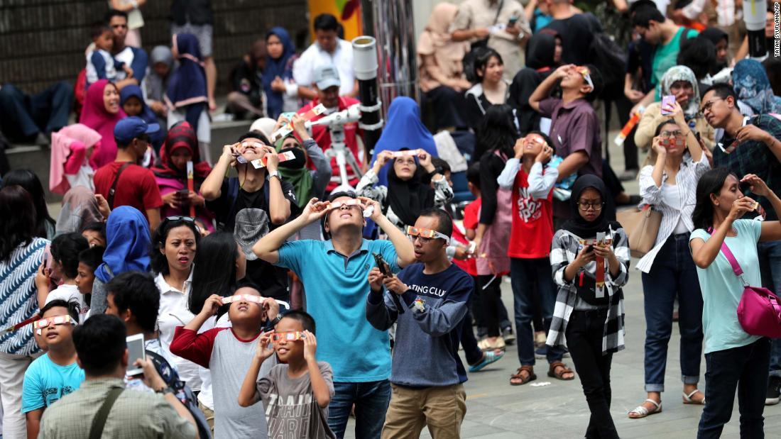 日食グラスを装着して観測する人々＝インドネシア/Tatan Syuflana/AP