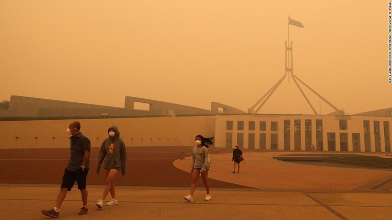 森林火災で発生した煙が立ち込めるキャンベラの街を、マスクをして歩く人々/Alex Ellinghausen/The SMHFairfax Media via Getty Images